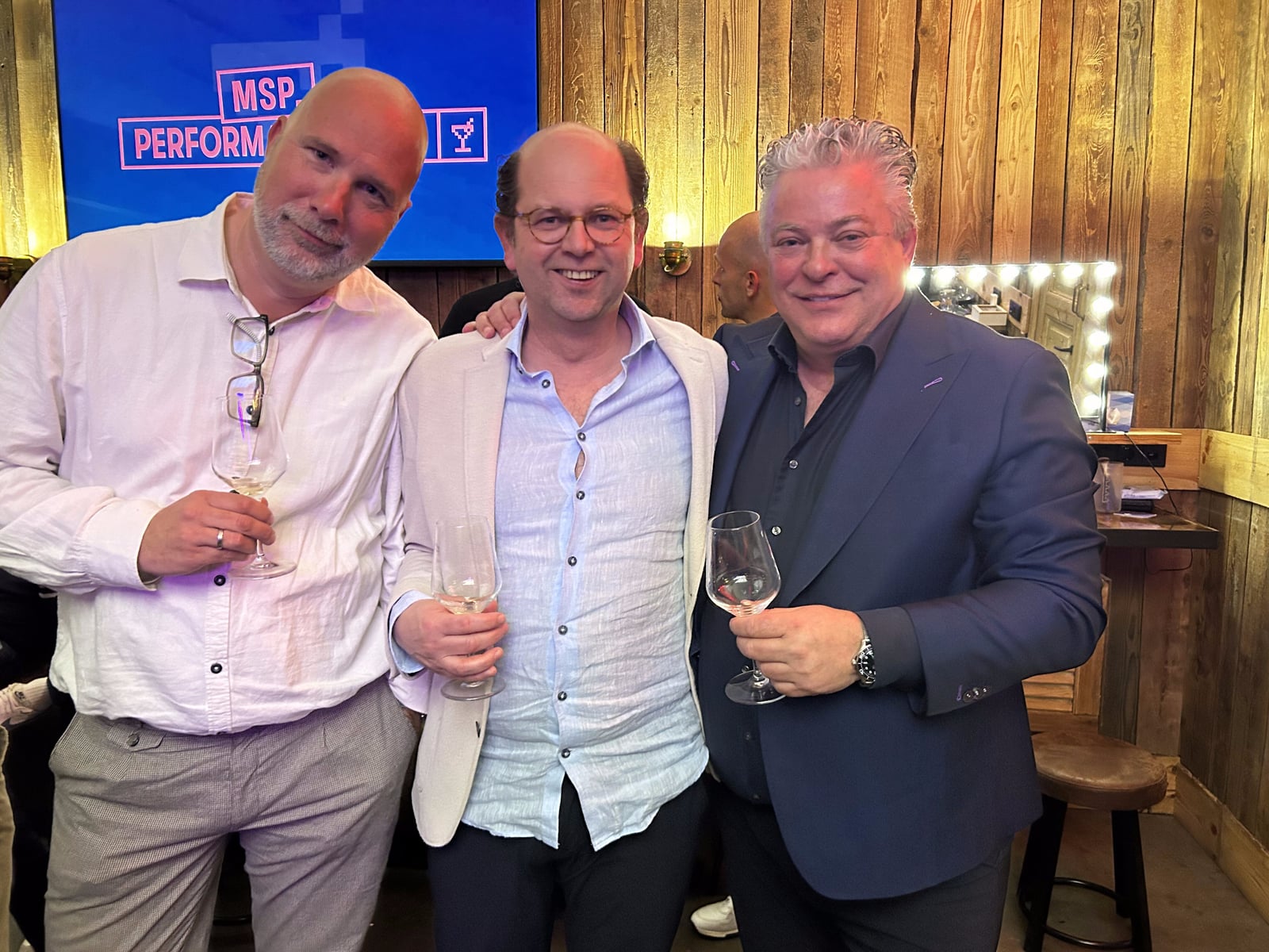 Drie bezoekers met een glas voor het scherm van MSP Performance Club