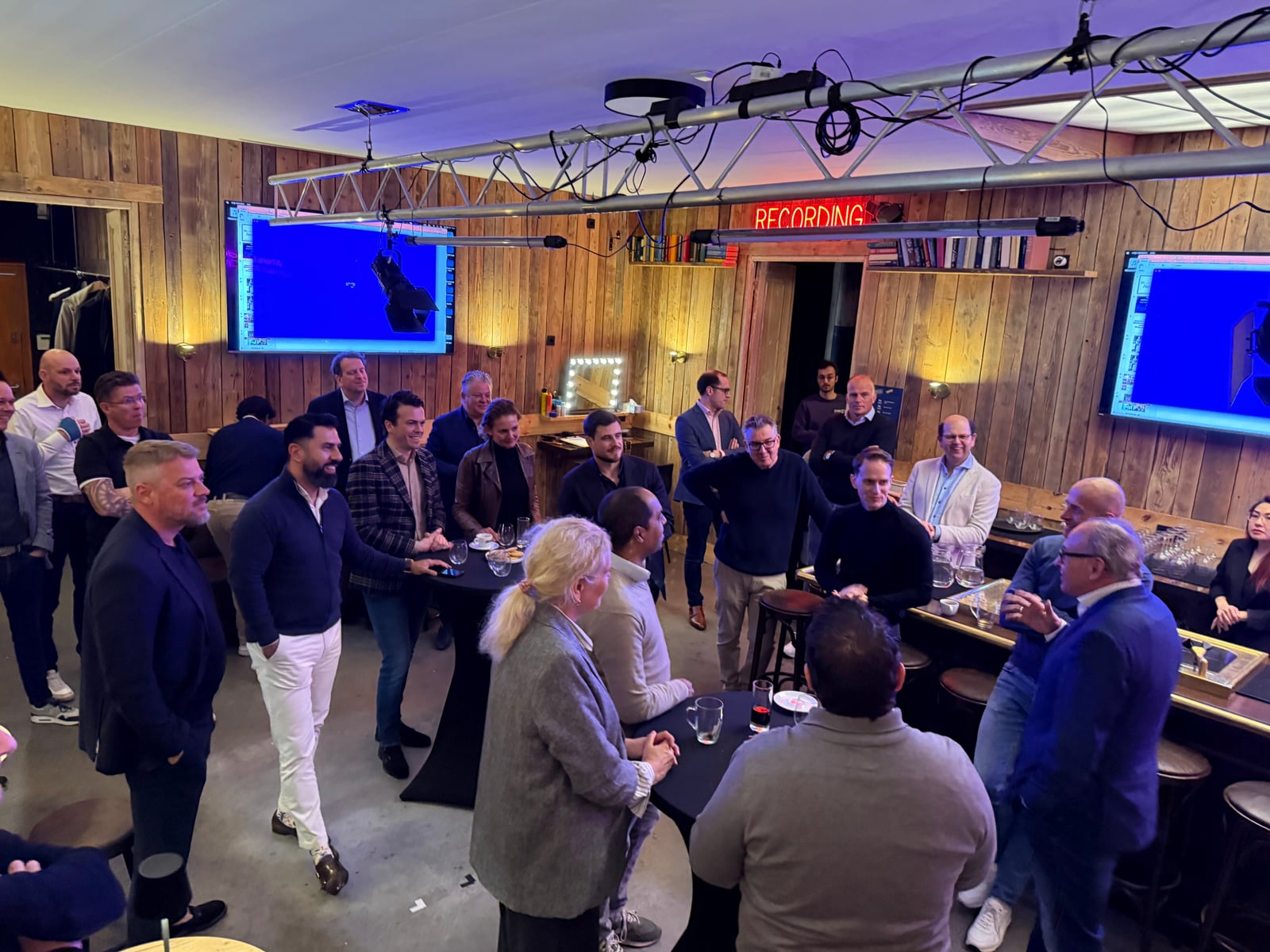 Bezoekers napraten in de studio, met schermen aan de wand