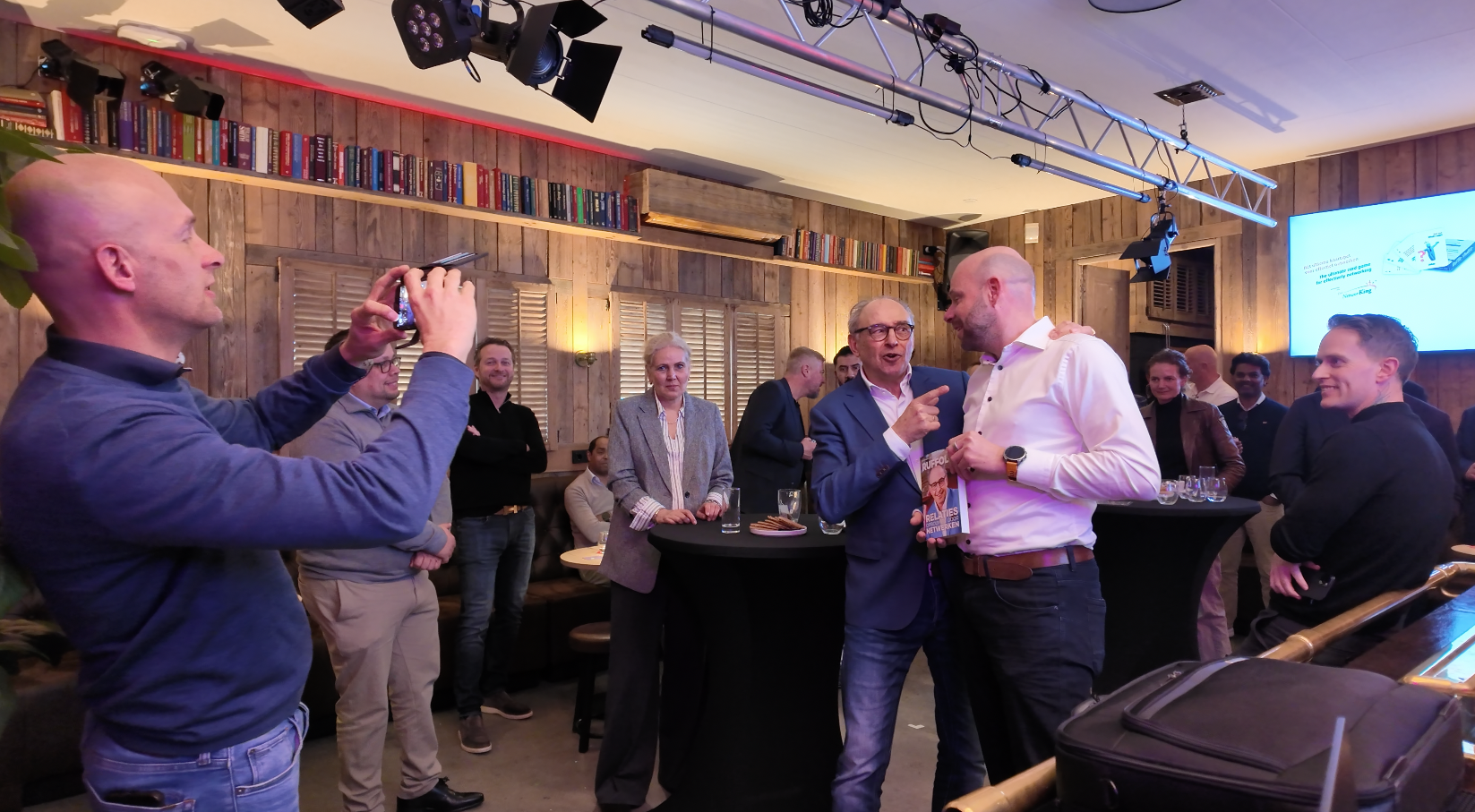 Overzicht van de zaal tijdens de borrel, iemand maakt een foto